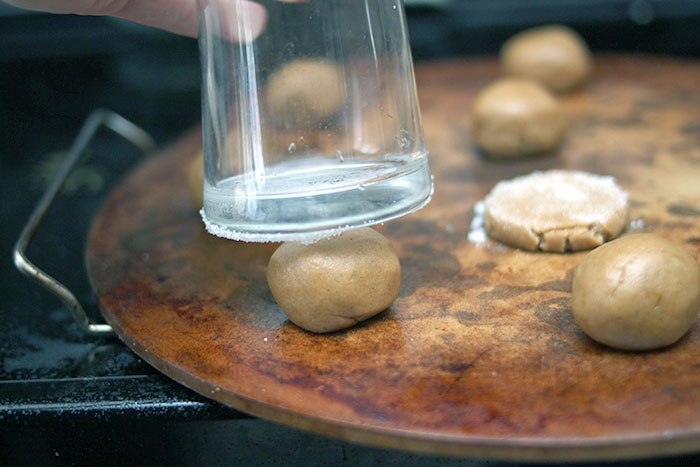 pressing down molasses cookies to prepare for baking